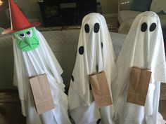 two white ghost costumes with green faces and black noses are standing in front of a couch