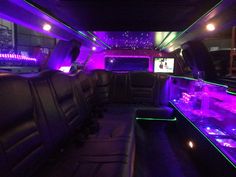 the interior of a limo with purple and green lights on it's walls, along with black leather seats