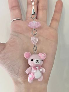 a hand holding a pink teddy bear keychain on it's thumb with a chain attached to it