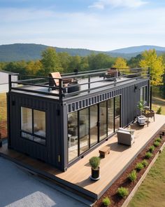 a house made out of shipping containers on top of a hill with trees in the background