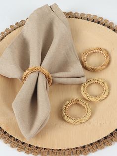 the napkin is next to three rings on top of a wooden platter with a cloth