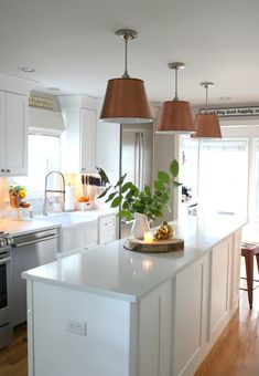 a kitchen with white cabinets and an island in the middle is lit by two hanging lights