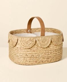 an empty basket with leather handles on a white surface