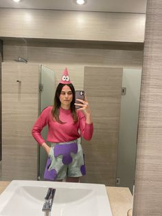 a woman taking a selfie in front of a bathroom mirror wearing a birthday hat