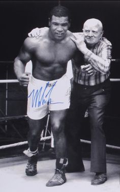 two men standing next to each other in a boxing ring with one holding his arm around the other