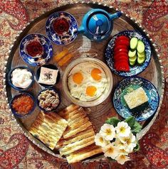 an assortment of food is arranged on a platter with teapots and saucers