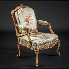 an ornately decorated chair with gold trimmings and flowers on the upholstered back