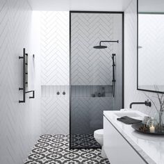 a bathroom with black and white tiles on the floor, shower stall and sink area