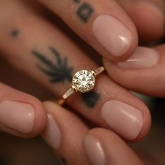 a close up of a person's hand holding a ring with a diamond on it