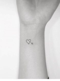 a small wrist tattoo with a heart and an arrow on the left side of the arm