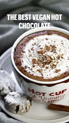 a cup of hot chocolate with whipped cream on top and cinnamon sticks next to it