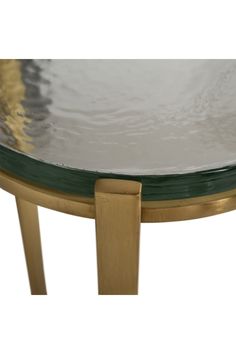 a round glass table with wooden legs and gold trimming on the top, against a white background