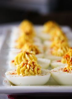 deviled eggs on a white plate with red chili sprinkles and text overlay that reads deviled eggs