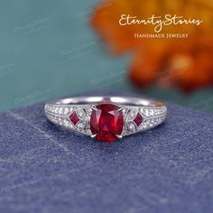 a close up view of a ring with a red stone in the center and diamonds around it