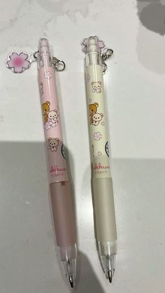 two pens sitting next to each other on top of a white table with pink flowers