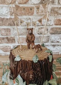 there is a cake that looks like a log with a bear on top and bunting