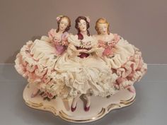 three figurines sitting on top of a white plate with pink trimmings