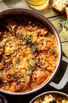 an overhead view of a pot of pasta with meats and cheese on the side