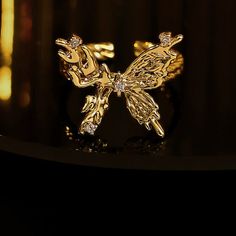 ✦ Indulge in the elegance of our Chunky 18K Gold Butterfly Cocktail Ring made with molten design and 18k gold plating. Perfect for any occasion, this statement ring features a bold butterfly design, adjustable fit, and serves as a luxurious gift for friends. Elevate your style with this exclusive piece that exudes sophistication and uniqueness. ----------- DETAILS ----------- - Color: Gold - Ring Size: 17.3mm (Approximately to Size US7) - Width: 1.8cm - Materials: 18K Gold Plated, Cubic Zirconia Adjustable Gold Butterfly Open Ring, Gold Luxury Butterfly Ring For Formal Occasions, Luxury Gold Butterfly Ring For Formal Occasions, Elegant Adjustable Gold Butterfly Ring, Luxury Gold Butterfly Ring, Adjustable Gold Butterfly Ring, Luxury Gold Butterfly Ring As Gift, Luxury Gold Butterfly-shaped Ring, Gold Formal Butterfly Ring