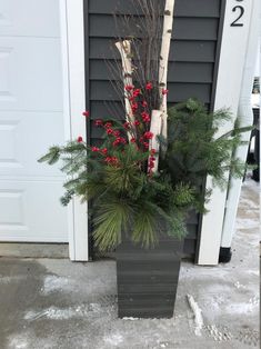 a tall planter filled with evergreen and red berries