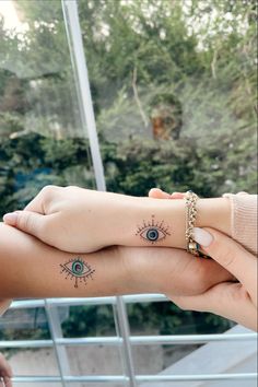 two people holding each other's hands with tattoos on their wrists and fingers, both showing