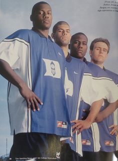 a group of men standing next to each other in front of a blue and white shirt