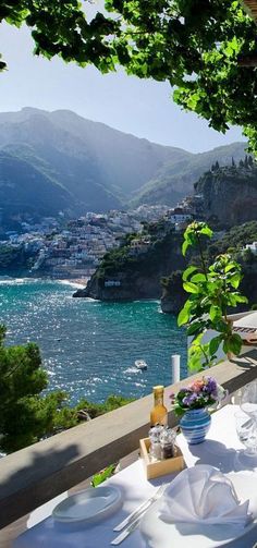 an outdoor dining area overlooking the water and mountains with white table cloths on it