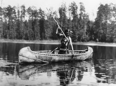 an old black and white photo of a man in a canoe