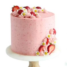 a pink cake with strawberries and daisies on top