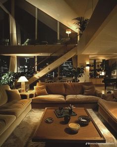 a living room filled with lots of furniture next to a window covered in lights and plants