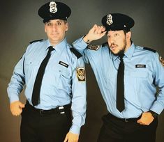 two police officers in blue shirts and ties are posing for a photo with their hands on their head