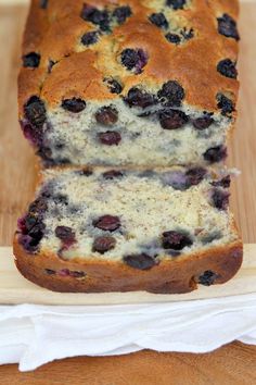 a loaf of blueberry bread sitting on top of a wooden cutting board