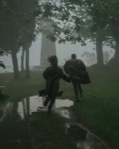 two people running in the rain with umbrellas