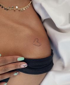 a woman's breast with a heart tattoo on it