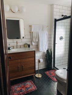 a bathroom with black and white tile, wooden vanity, toilet and shower stall in it