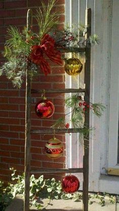 an old ladder is decorated with ornaments and greenery for the holiday season in front of a house