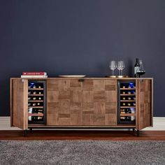 a wooden cabinet with wine bottles and glasses on it in front of a gray wall