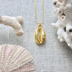 We love this fun and summery, beachy necklace. Answer the siren's song and get one for yourself or someone you love. Would make a great gift for the surfer or beach-lover in your life! A 14k gold electroplated cowrie shell dangles from a lustrous, high quality gold filled snake chain. The perfect summertime accessory! Chain: Gold fill, length 16" Cowrie Pendant: 22k Gold plated size: 26 x 18 mm✦ JEWELRY CARE ✦✧ Warm water and a soft cloth are the best thing you can do to maintain the beauty of y Gold Starfish Charm Necklace For Beach Season, Gold Necklace With Starfish Charm For Beach Season, Ocean-inspired Charm Necklace For Summer Beach, Summer Beach Ocean-inspired Charm Necklaces, Ocean-inspired Summer Beach Charm Necklace, Summer Beach Ocean-inspired Charm Necklace, Starfish Charm Necklace For Beach Season Gift, Ocean-inspired Strand Charm Necklaces As Gift, Beach Jewelry With Charms In Ocean-inspired Style