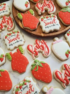 some decorated cookies are on a table and there is a wooden platter full of them