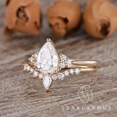 an engagement ring with a pear shaped diamond surrounded by smaller pears on a wooden table