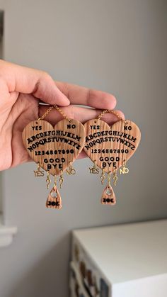 a pair of wooden earrings with words written on the front and back, hanging from gold - plated earwires