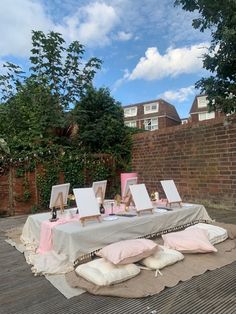 an outdoor table with paintings and pillows on it