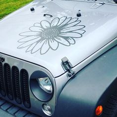 a silver jeep with a flower decal on the hood