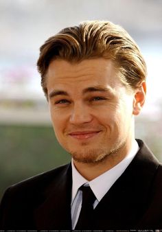 a close up of a person wearing a suit and tie with a smile on his face