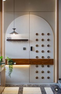 an entrance to a building with buttons on the wall and plants in pots next to it