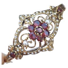 Vintage 14K Art Deco Hinged Bracelet 30s Garnet Seed Pearls Measurement: Oval hinged 2.25 inch by 2 inch Jewels: 9 round Garnet approximately 2.52 Carat Total weight, 1.5mm - 3.0mm white round Seed Pearls (one missing) Weight: 20.6 gram Country of origin: United States Hallmark: "14K" Victorian Bracelets With 17 Jewels For Evening, Vintage Ceremonial Jewelry With Screw Back, Antique Gold Hinged Bracelet For Wedding, Antique Hinged Gold Bracelet For Wedding, Antique Evening Bracelets, Ornate Hinged Jewelry For Wedding, Ornate Hinged Wedding Jewelry, Antique Hallmarked Gold Bracelet For Wedding, Antique Gold Bracelet For Wedding