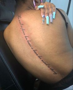 the back of a woman's body with writing on her left side and two toothbrushes in her other hand