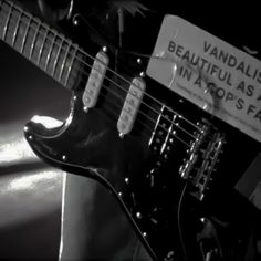 a black and white photo of an electric guitar with a sign on it's neck