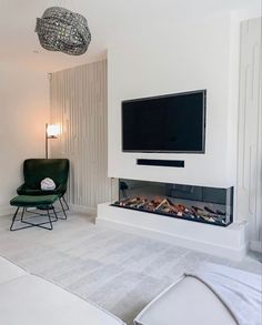 a living room with a large flat screen tv on the wall and a green chair