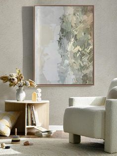 a living room with a white chair and a painting hanging on the wall above it